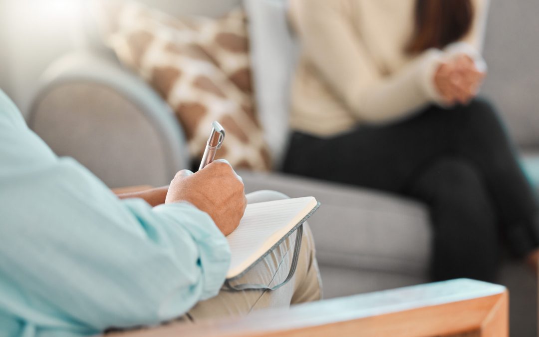 Sesión de terapia cognitivo conductual con psicólogo tomando notas