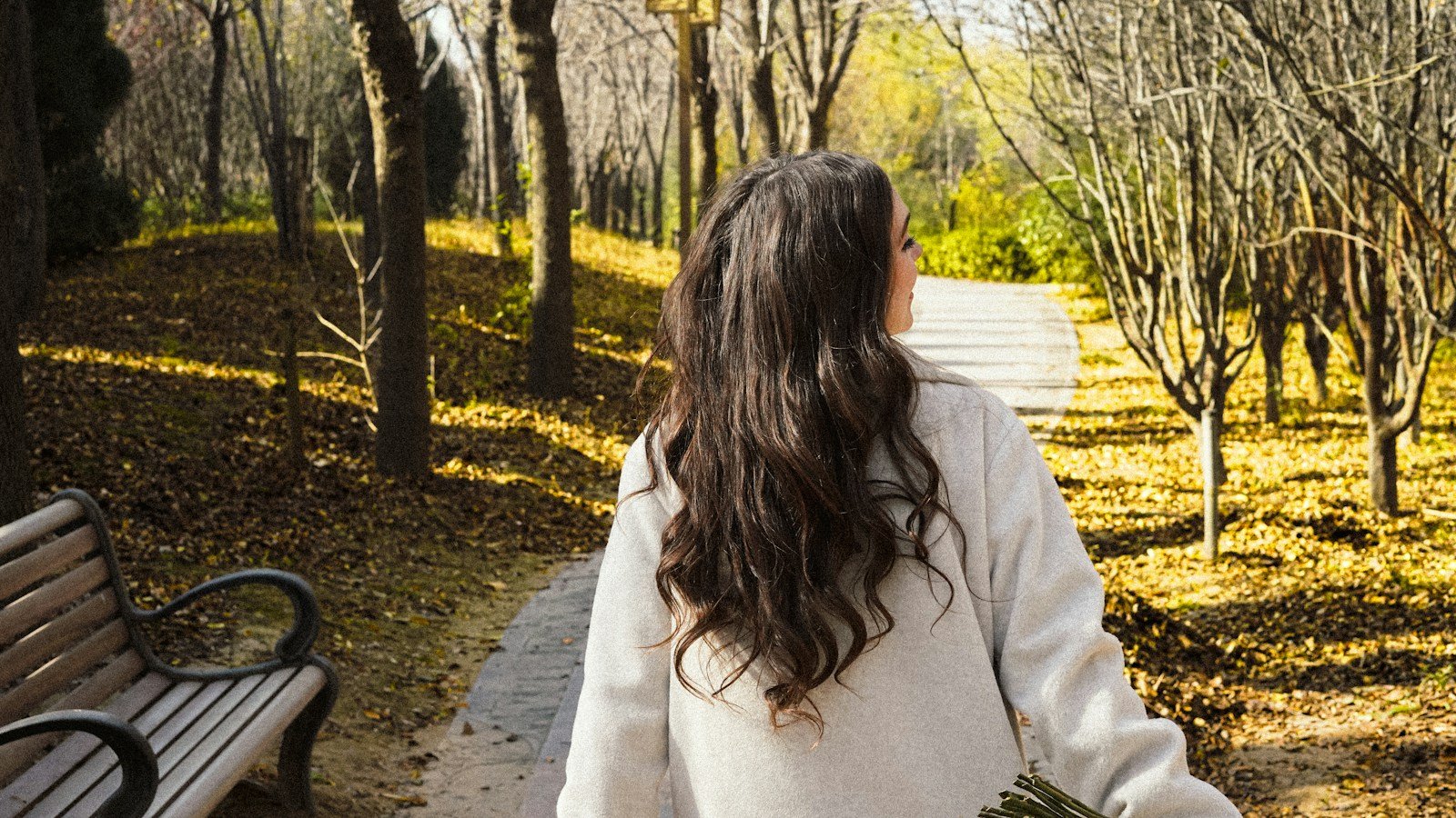 Mujer caminando sola por un sendero de parque urbano en una tarde tranquila